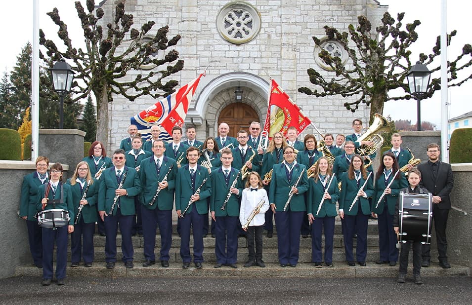 La société de musique Broc-Estavannens devant l'église, avec ses drapeaux.